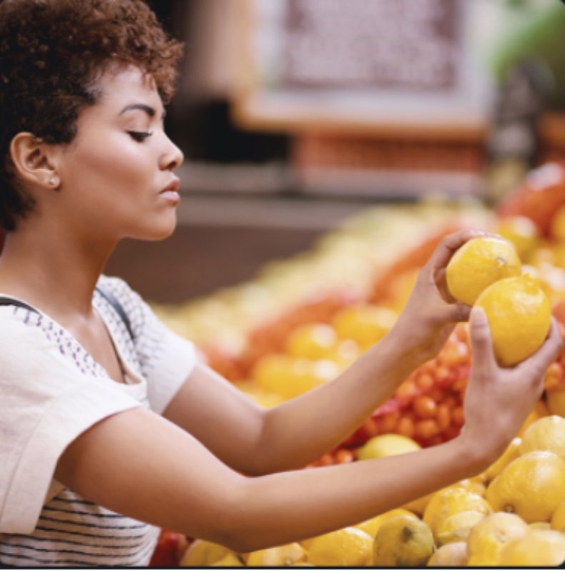 A young woman carefully selecting fresh produce at Uncle May's Produce